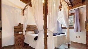 A bedroom with a wooden bed, a nightstand, and a canopy bed. - Vacation Home "Casa Rural Romance" with Sea View, Jacuzzi & Wi-Fi (Icod de los vinos)