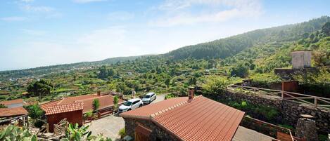 Un entorno rural con edificios de piedra, una zona pavimentada y vehículos.