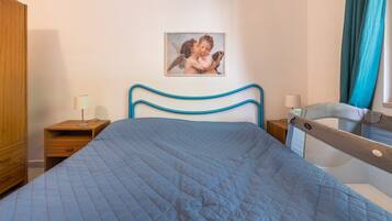 Une chambre à coucher comprenant un lit, une table de chevet, une armoire en bois et un tableau accroché au mur.