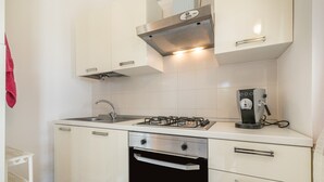 A kitchen with white cabinets, a gas stove, a built-in oven, and a coffee maker. - Villa 'Villetta Teresa' with Sea View, Private Garden, Terrace & A/C (Costa Rei)
