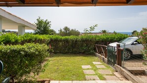 A covered outdoor area with a wooden ceiling, a stone pathway, and a car parked beside a green fence. - Villa 'Villetta Teresa' with Sea View, Private Garden, Terrace & A/C (Costa Rei)