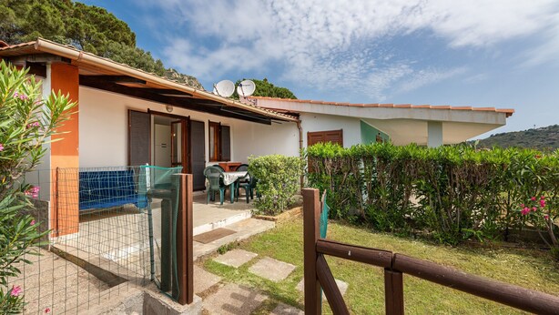 A house with a patio, a fenced area, and a view of the surrounding greenery. - Villa 'Villetta Teresa' with Sea View, Private Garden, Terrace & A/C (Costa Rei)