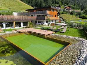 Un hotel moderno con piscina, mobiliario exterior y vistas a las colinas circundantes.