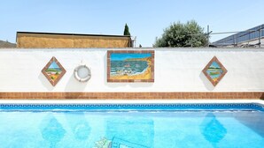 Ein Schwimmbecken mit Mosaikfliesen, einem Rettungsring und zwei gerahmten Bildern an der Wand.