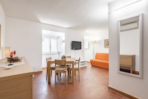 A modern living room with a dining area, a television, and a sofa.