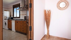A kitchen with wooden cabinets, a washing machine, and a microwave. - Holiday Apartment 'Villa Fornell Atico' with Shared Pool, Terrace and Wi-Fi (Conil)