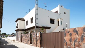 A two-story house with a gated entrance, a ladder, and a clear sky. - Holiday Apartment 'Villa Fornell Atico' with Shared Pool, Terrace and Wi-Fi (Conil)