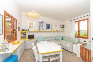 A compact kitchen with a dining area, a sofa, and a window with a view.