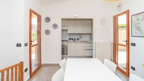 Una cocina moderna con armarios blancos, una mesa de comedor con sillas y vistas al exterior.