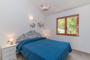 A bedroom with a bed, nightstands, wall art, a window, and a ceiling decoration.