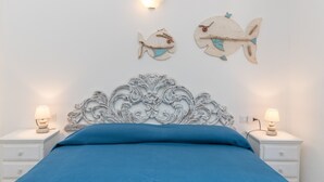 Un dormitorio con una cama, dos mesitas de noche, una lámpara de pared y una decoración de peces en la pared.