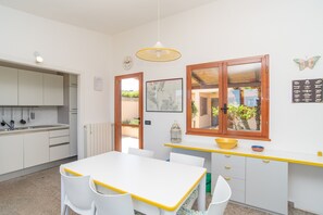 A modern kitchen with white cabinets, a yellow countertop, and a dining area with white chairs.