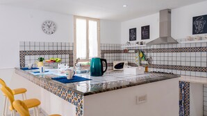 Una cocina moderna con una isla central, taburetes de bar, un reloj y baldosas decorativas.