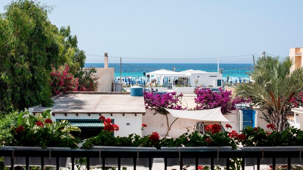 Un hotel frente al mar con terraza en la azotea, piscina y vistas al océano.