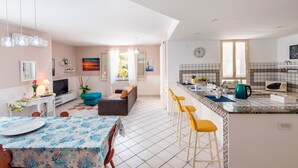 Una cocina moderna con una isla grande, taburetes de bar y un comedor con mesa y sillas.
