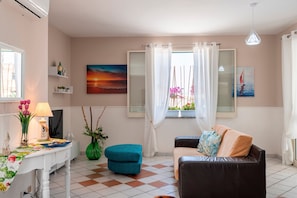 A living room with a sofa, ottoman, and a table with a lamp and decorative items.