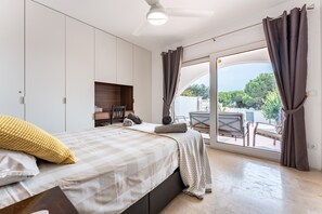 Une chambre à coucher comprenant un lit, un bureau, une chaise, une fenêtre avec des rideaux et une vue sur l’extérieur.