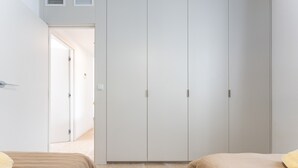A bedroom with two beds, a wardrobe, and a door leading to another room.
