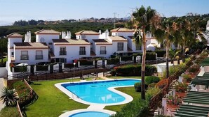 A resort with multiple white buildings, a swimming pool, and palm trees.