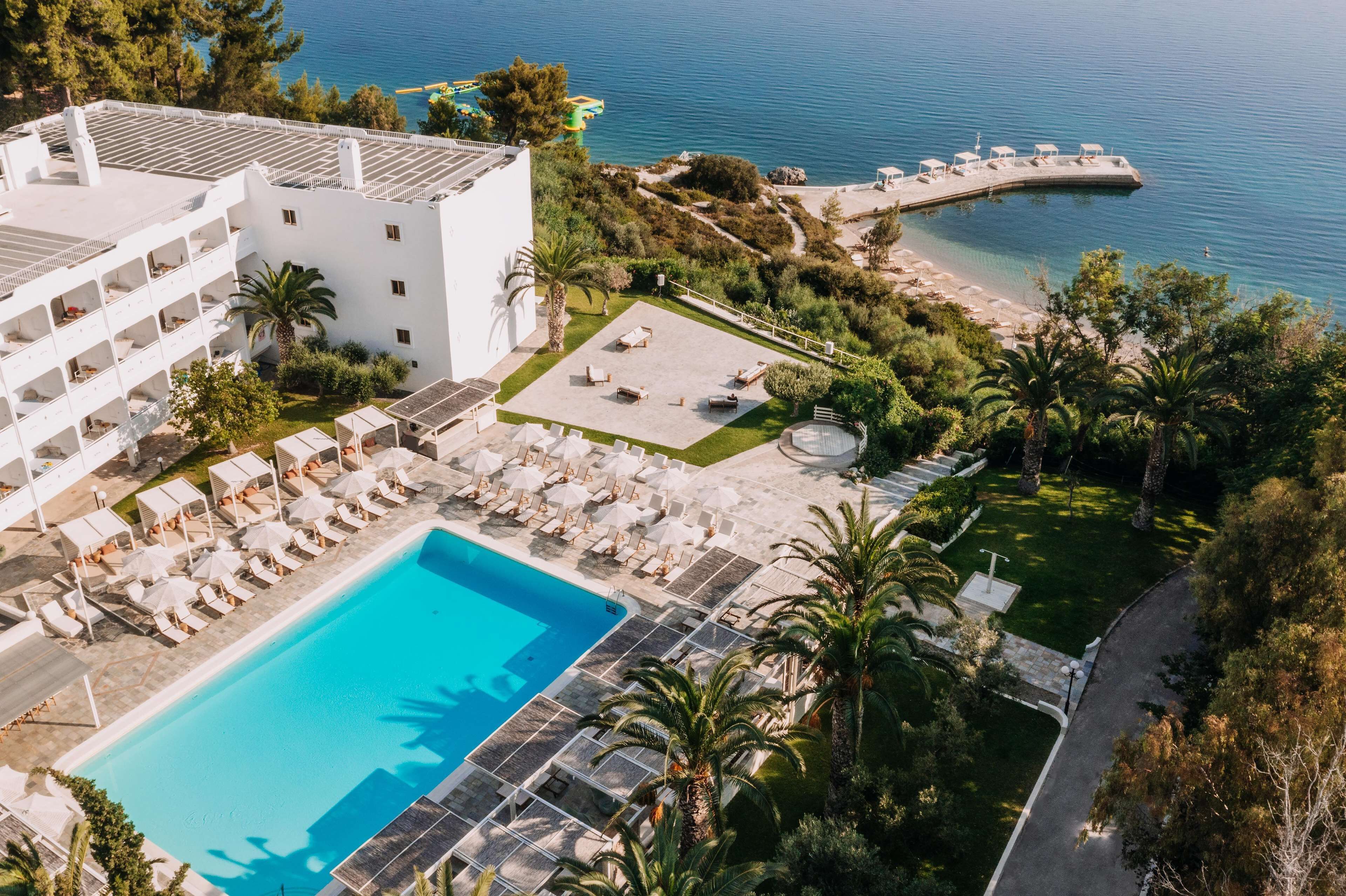A resort with a swimming pool, lounge chairs, and a beach area.