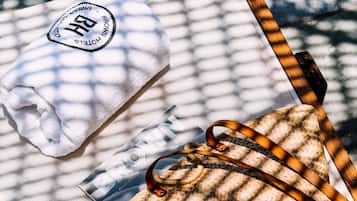 Una bolsa tejida y una toalla blanca con un logotipo sobre una superficie estampada.
