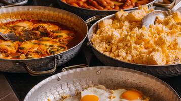 A variety of dishes including scrambled eggs, sausages, and vegetables on a buffet table.