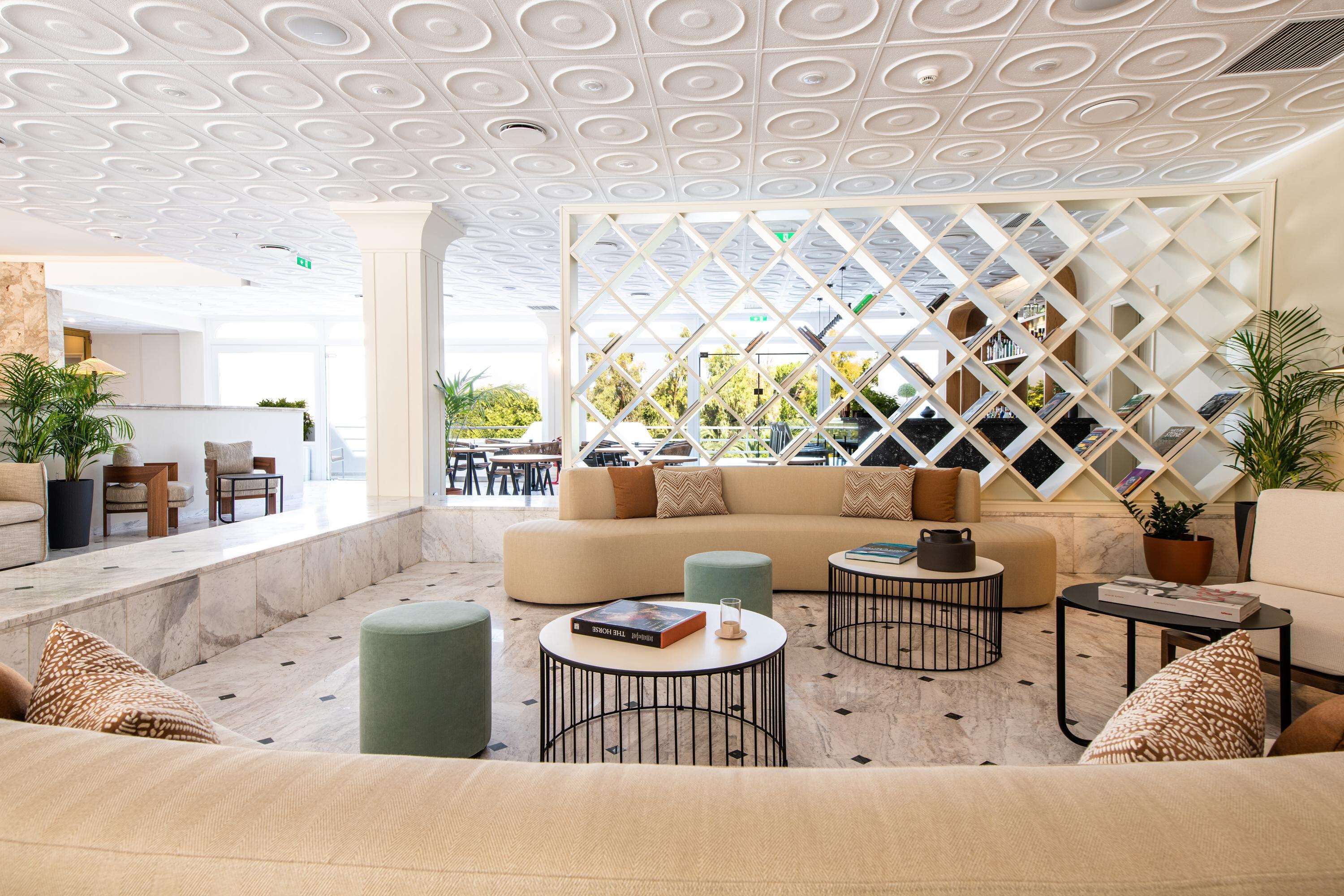 A modern lounge area with a sectional sofa, round coffee tables, and a decorative lattice wall.
