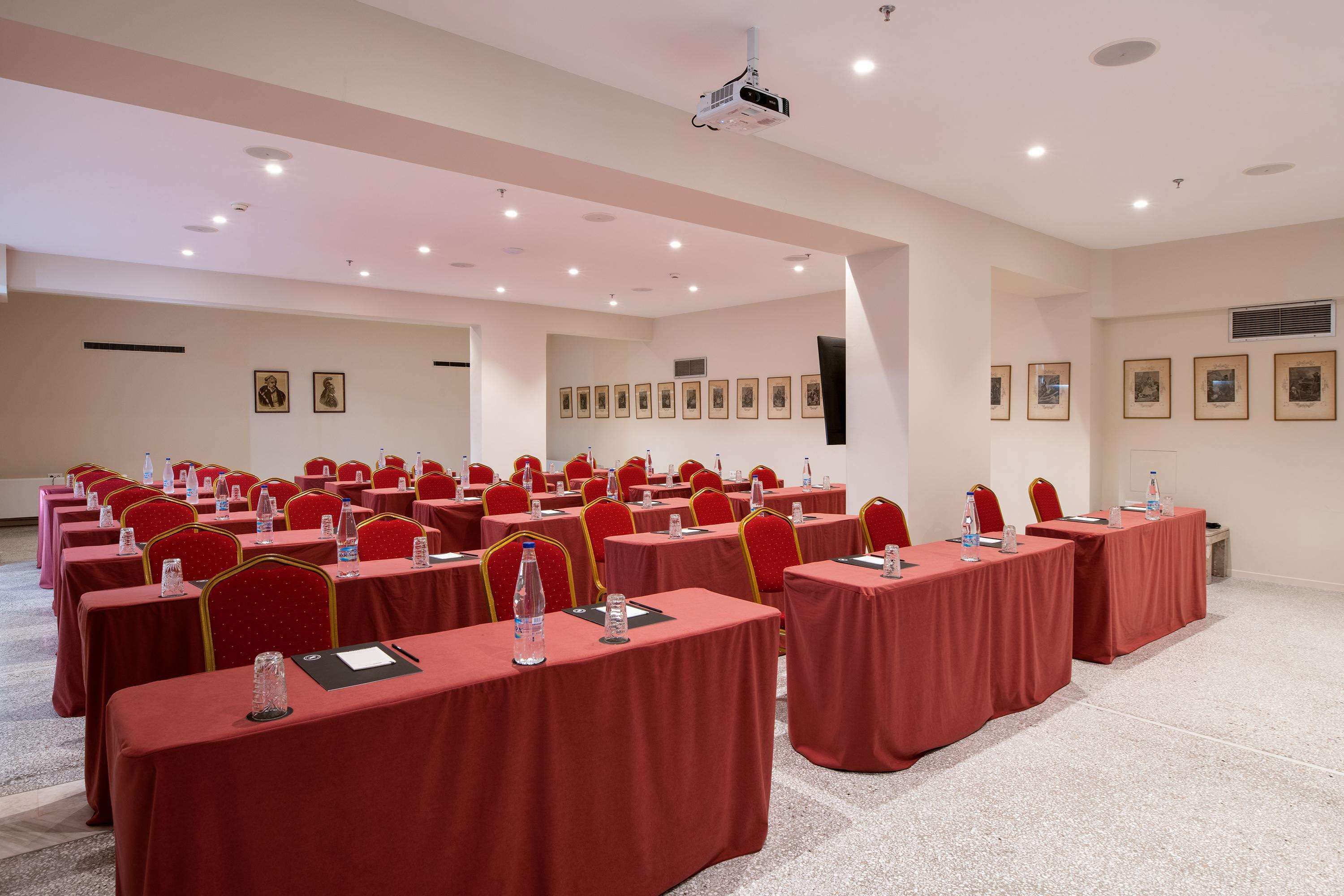 Un salón de conferencias con filas de mesas y sillas, equipado con botellas de agua y tarjetas de identificación.