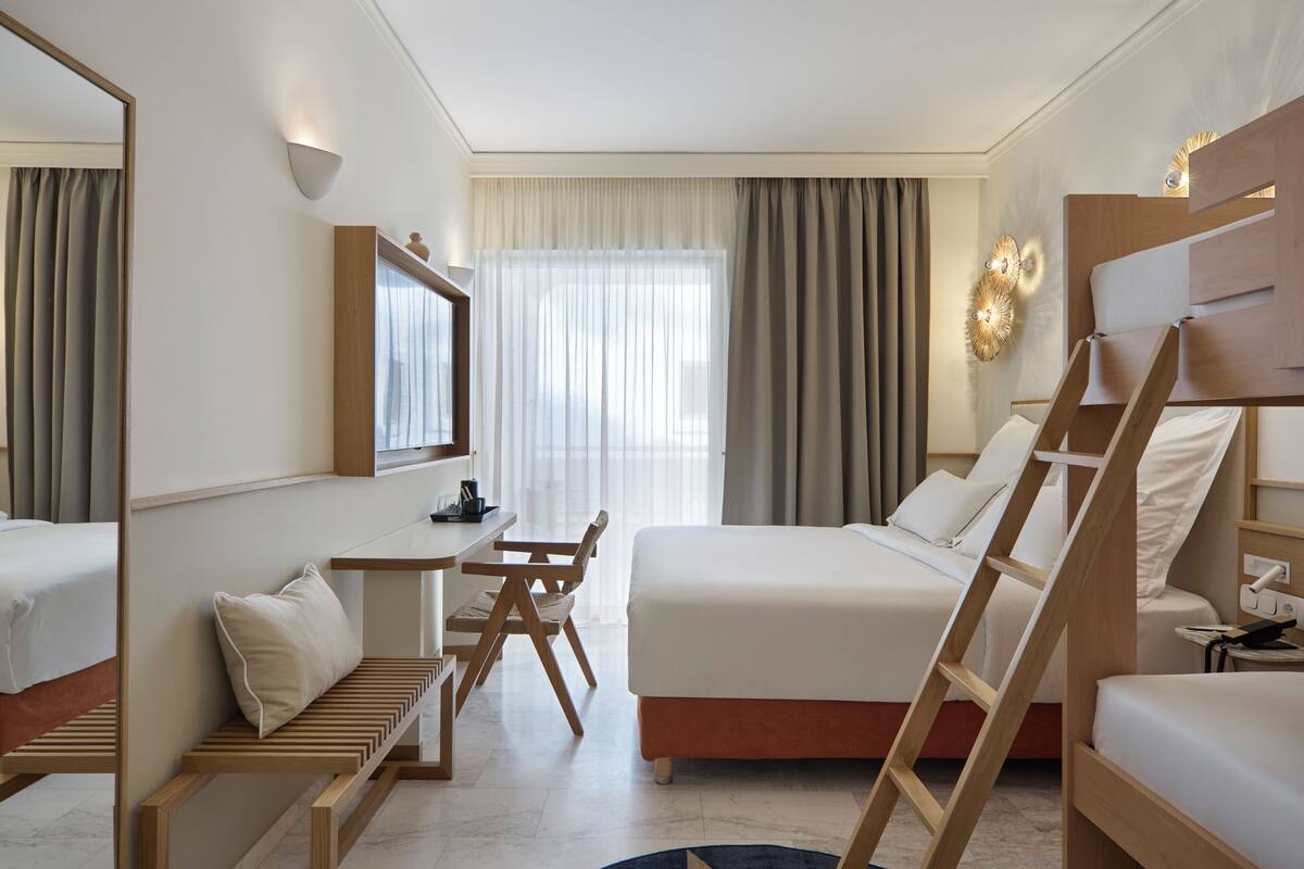 A hotel room with a bed, a desk, a chair, and a ladder.