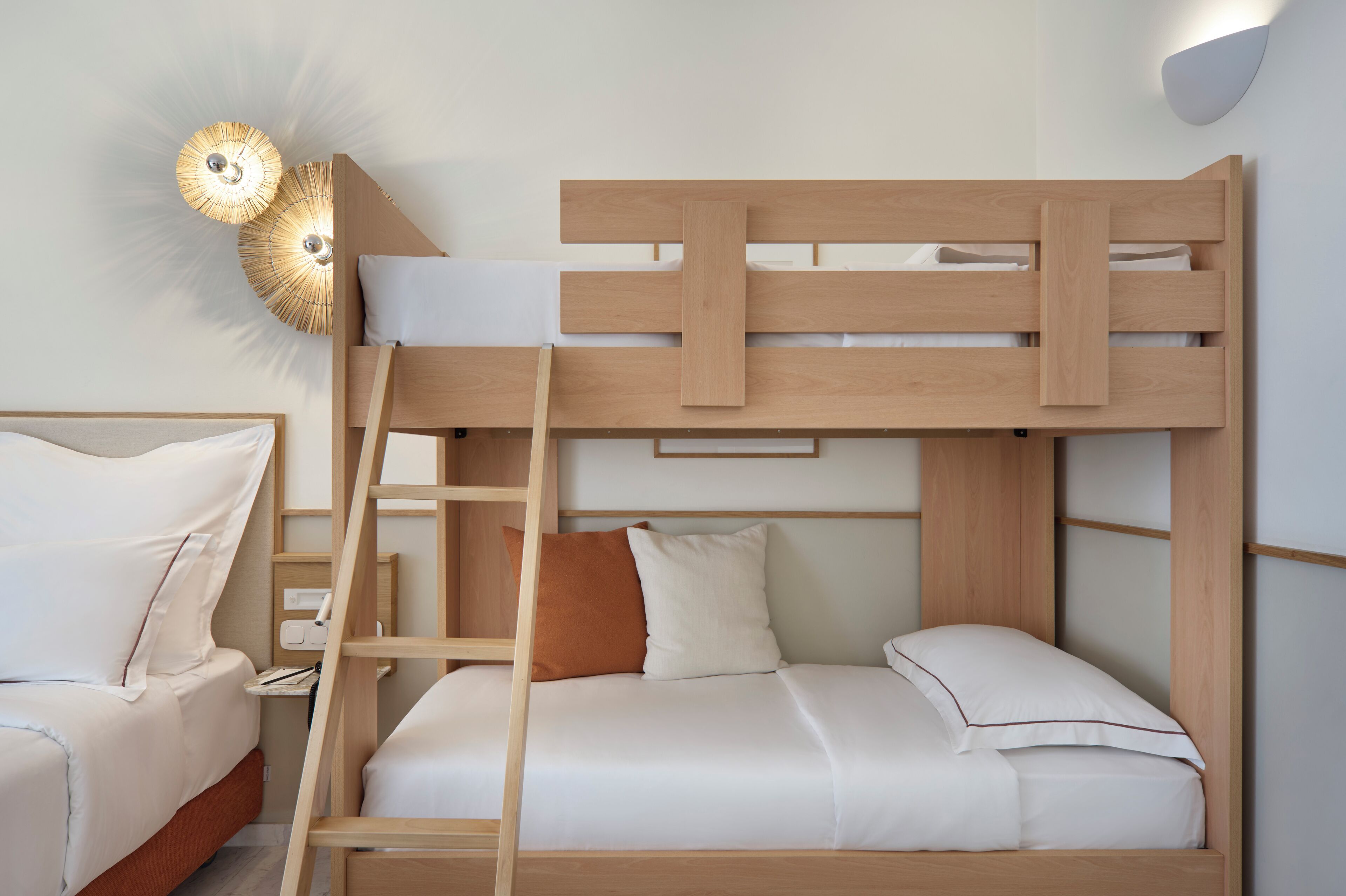 A bunk bed with a ladder, a bedside table, and a wall-mounted light fixture.