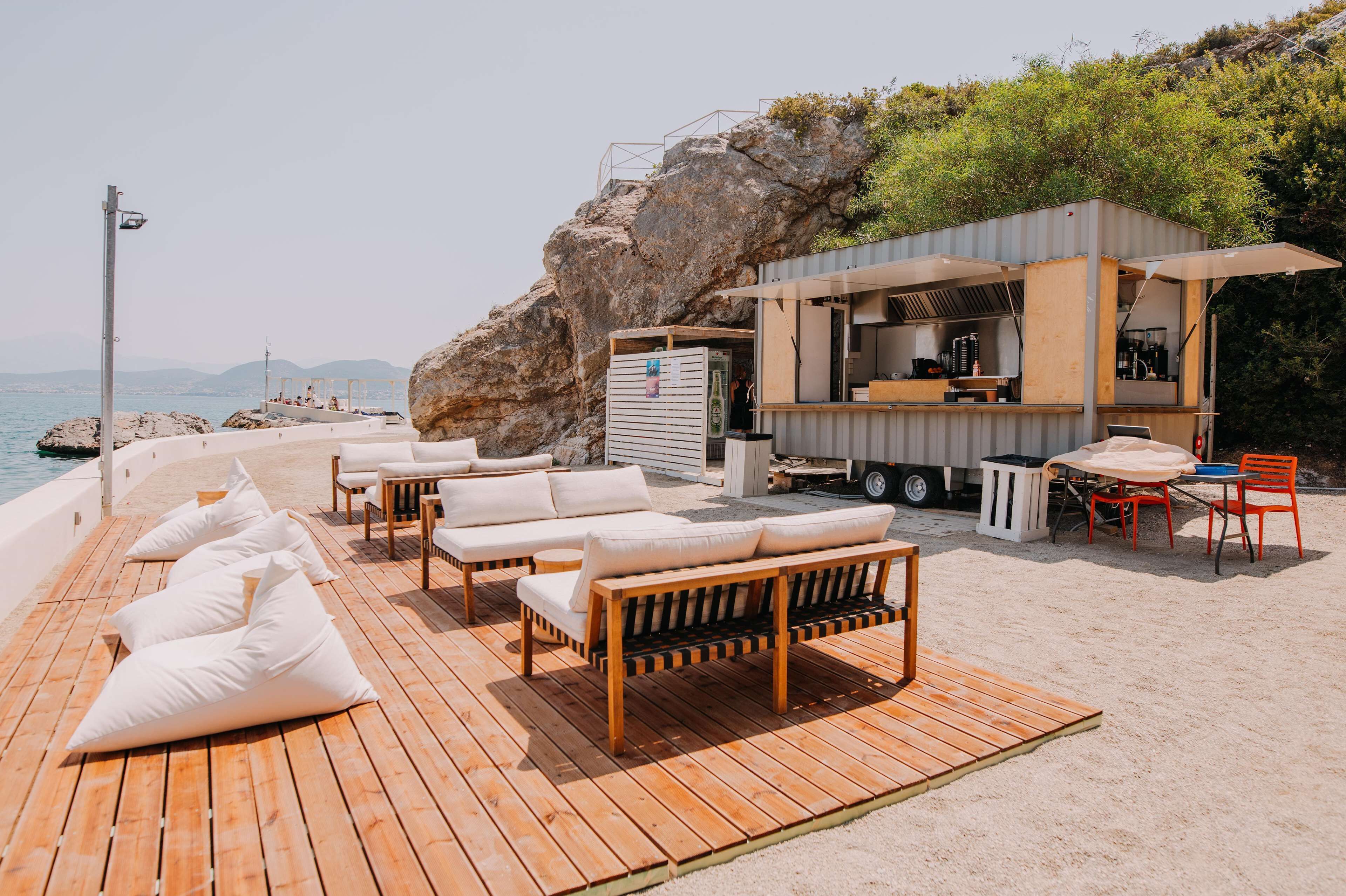 A wooden deck with white cushioned seating and a small outdoor kitchen area.