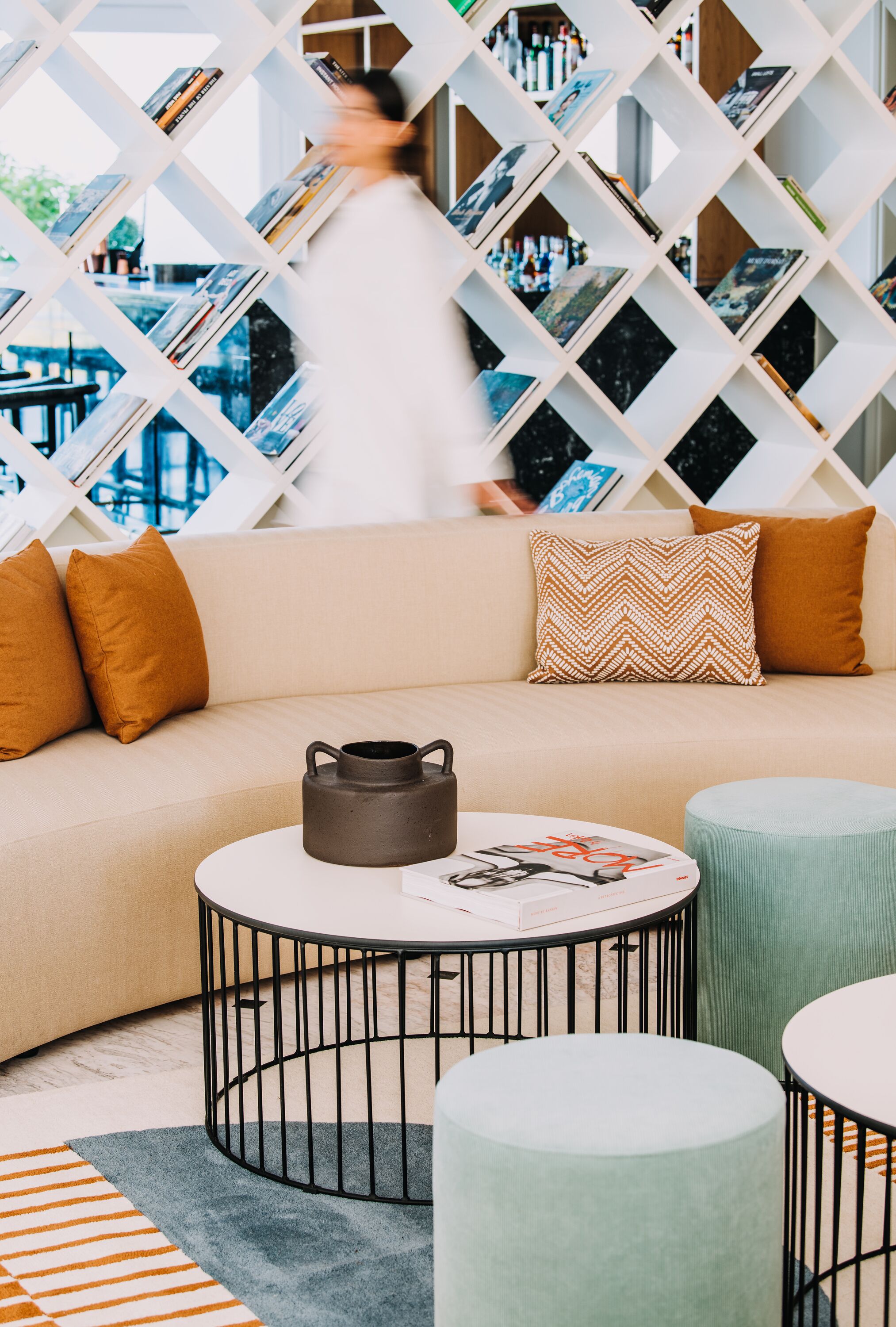 A modern living room with a sofa, two round tables, and a bookshelf.