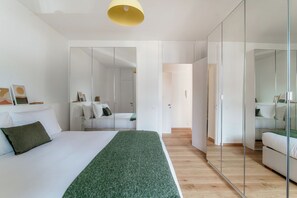 Ein modernes Schlafzimmer mit einem großen Bett, einer grünen Tagesdecke und einem Spiegelkleiderschrank.