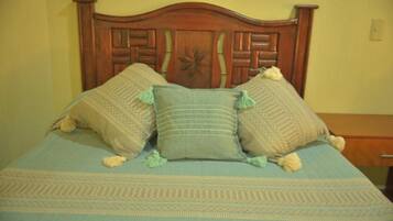 A bed with a wooden headboard, a patterned bedspread, and two decorative pillows.