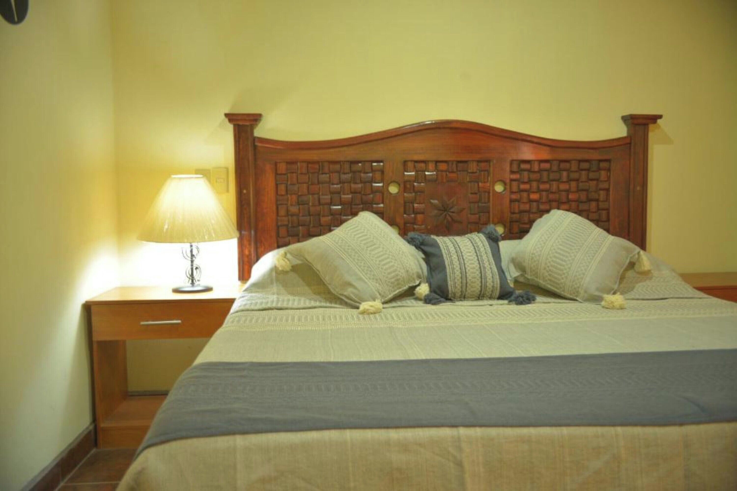 A bed with a wooden headboard, a bedside lamp, and a nightstand.