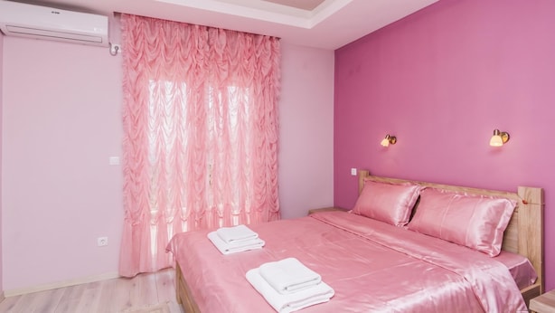 A bedroom with a pink wall, a bed with pink bedding, two bedside lamps, and a window with pink curtains. - Pool Villa Panorama Mojdez /w Sea View (Mojdez)