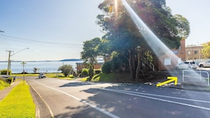 Una carretera costera con vistas al mar, un área de estacionamiento con automóviles y un edificio con un letrero que dice "Blue Vista".