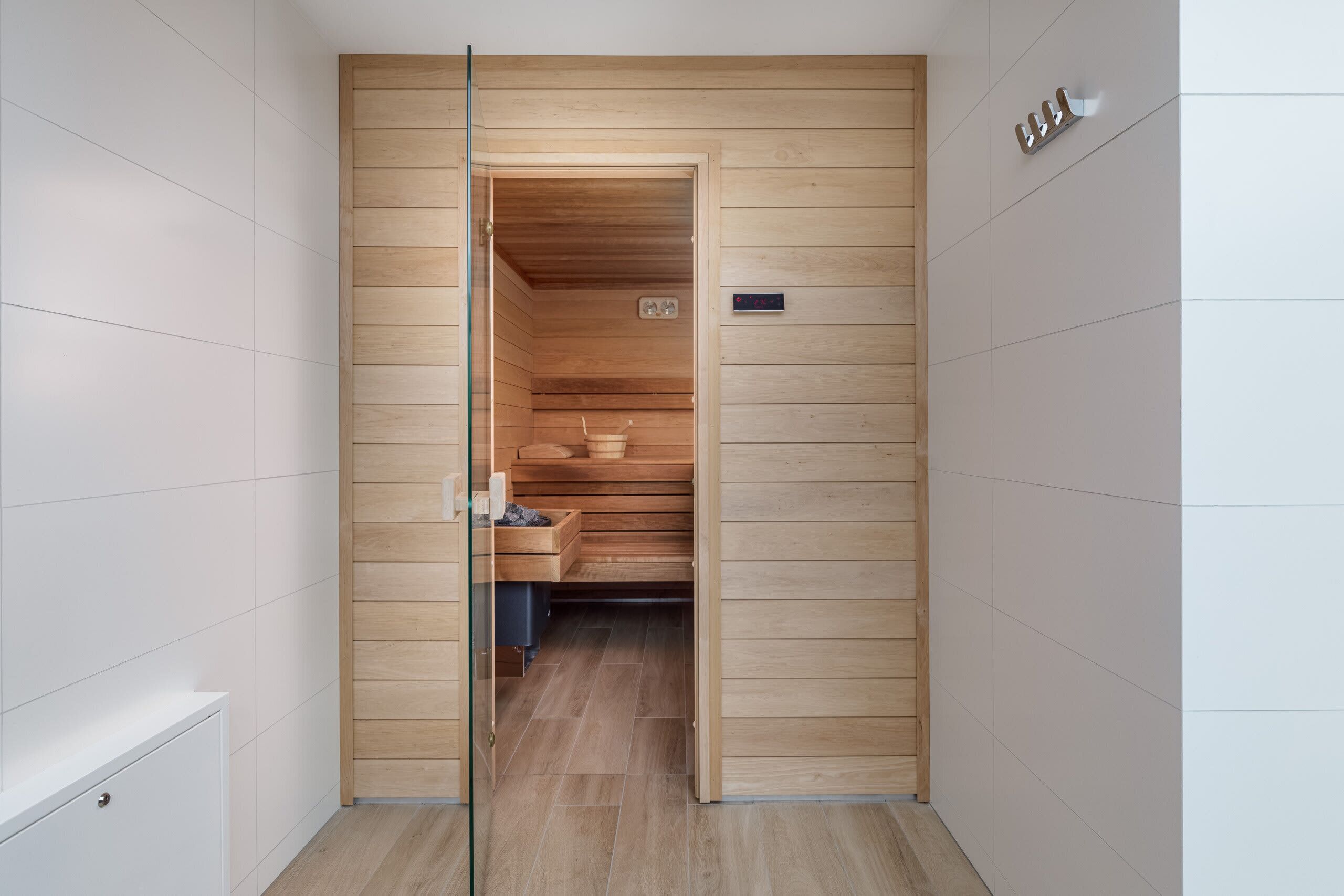 Une salle de bain moderne avec un lambris en bois, une cabine de douche en verre et un panneau de commande visible.