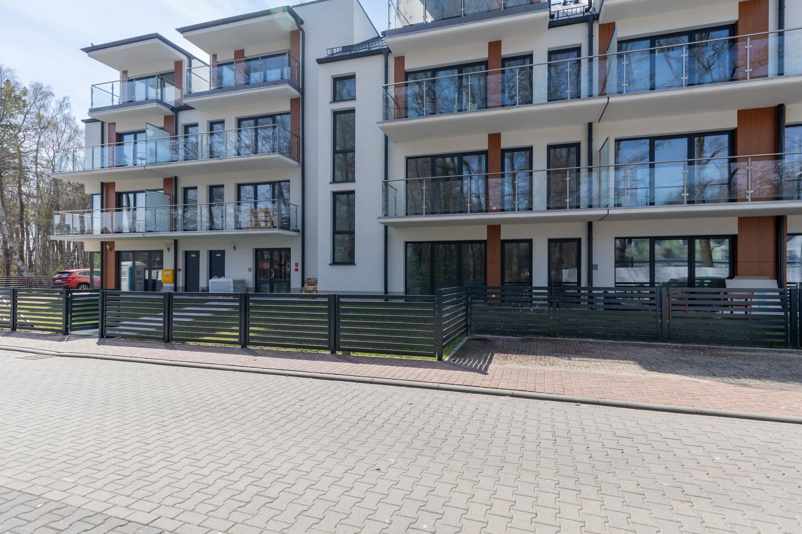 Een meerhoog gebouw met balkons, een verharde begane grond en een moderne architectuur.