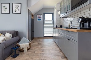 A modern kitchen with grey cabinets, a wooden countertop, and a coffee machine.