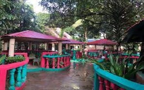 A covered outdoor area with tables and chairs, surrounded by greenery. - Kangs Hotel Malindi (Malindi)