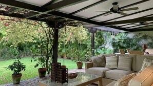 Veranda coperta con ventilatore a soffitto, divano e piante in vaso.