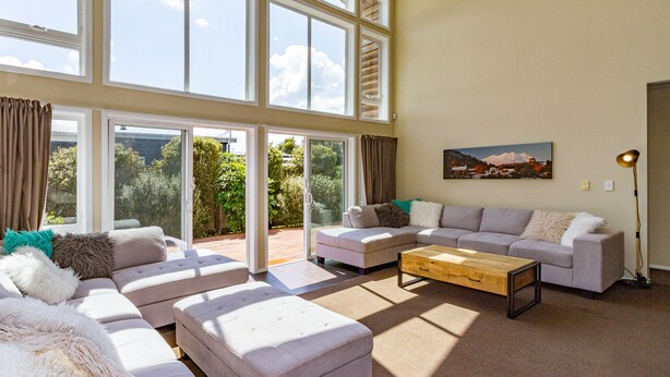 A spacious living room with large windows, a sectional sofa, and a coffee table.