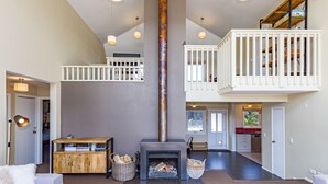 A spacious living area with a fireplace, wooden furniture, and a loft with a railing.