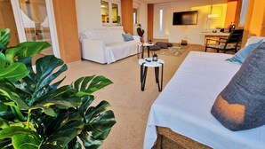 Une chambre d’hôtel avec un lit, un canapé blanc, une petite table et un téléviseur.