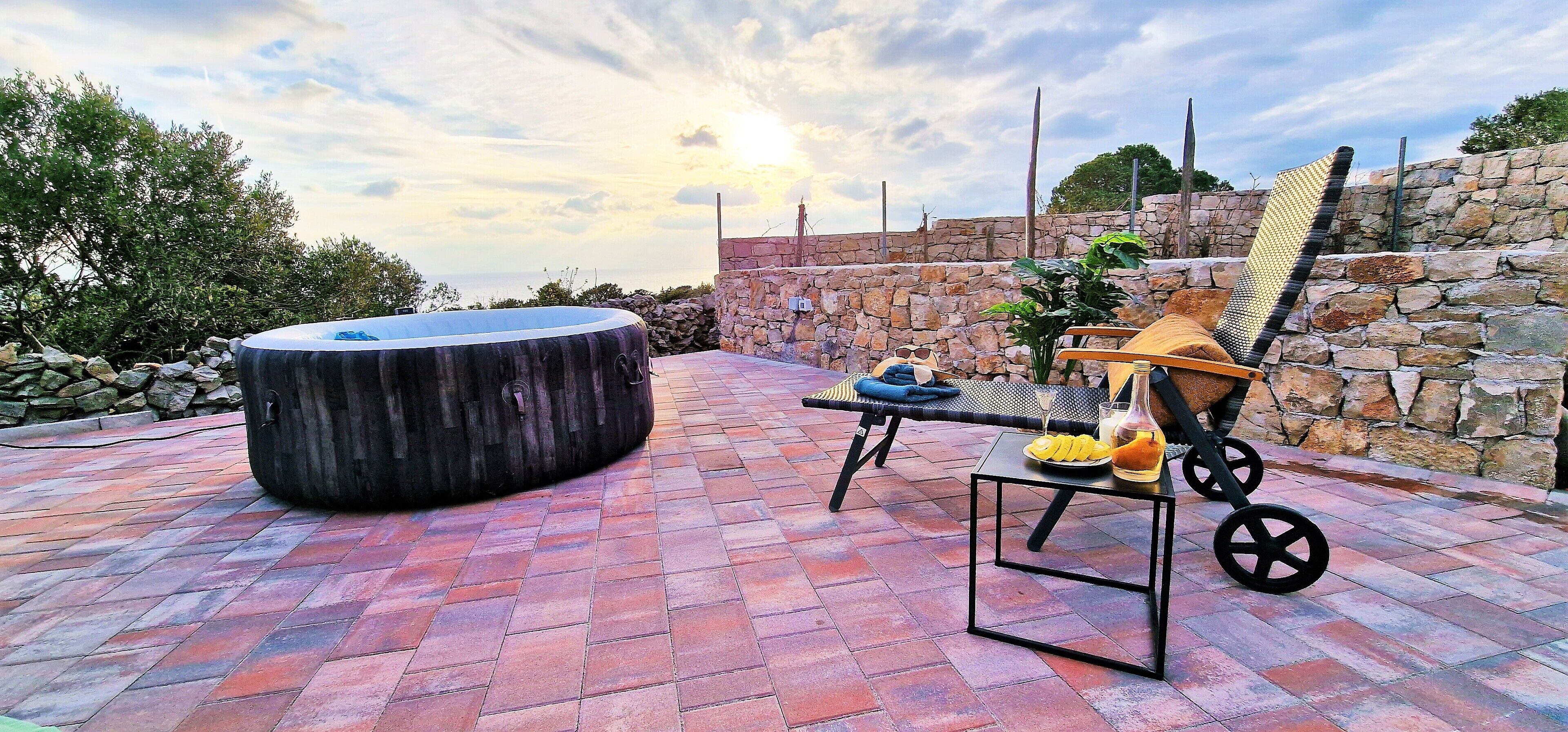An outdoor seating area with a hot tub, a table with a drink, and a chair.
