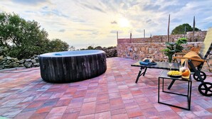 Un espace extérieur aménagé avec un coin salon, un jacuzzi, une table avec des boissons et une chaise.