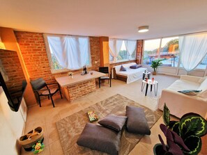 Uma sala de estar moderna com sofá, mesa de jantar e área de cozinha com parede de tijolos.