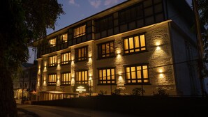 A multi-story building with illuminated windows and a sign that reads "Shinkham."
