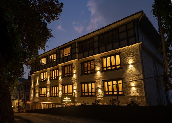 A multi-story building with illuminated windows and a sign that reads "Shinkham."